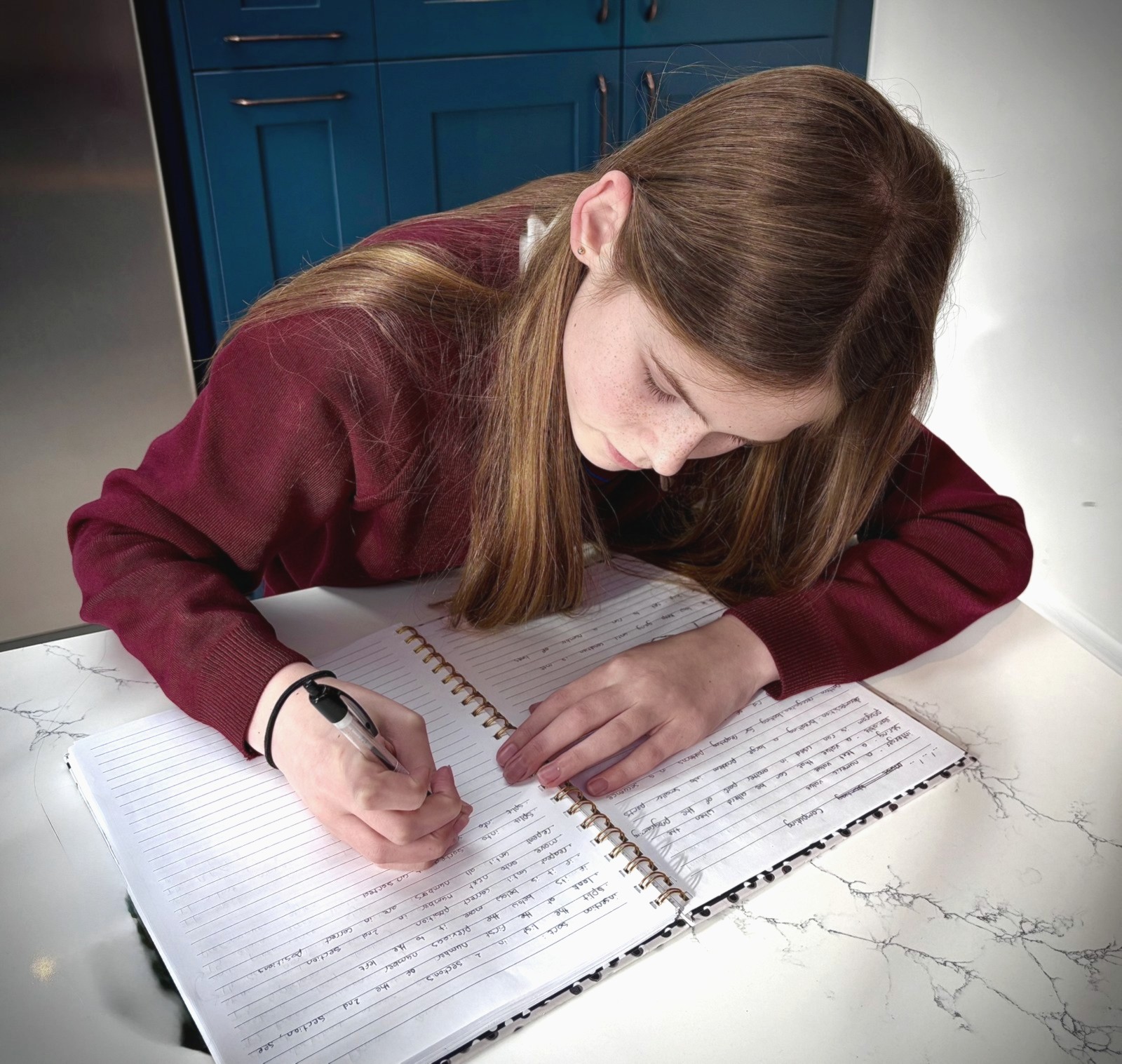 A teenage girl writing in a notebook