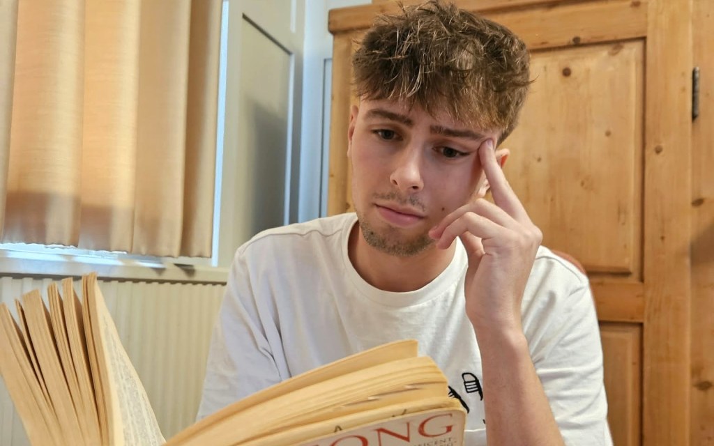 A young man reading a novel, thinking hard